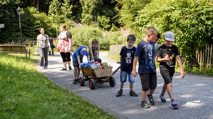 Mehrere Kinder gehen mit zwei Frauen und einem Bollerwagen durch das Museum