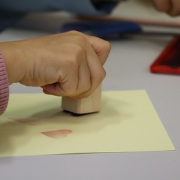 Eine Kinderhand stempelt ein Herz auf Papier