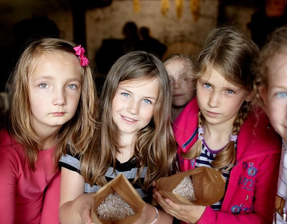 Mehrere Kinder sind zu Besuch im Museum und schauen frontal in eine Kamera