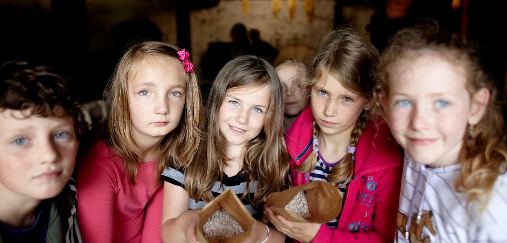 Mehrere Kinder feiern einen Kindergeburtstag im Museum und schauen frontal in die Kamera