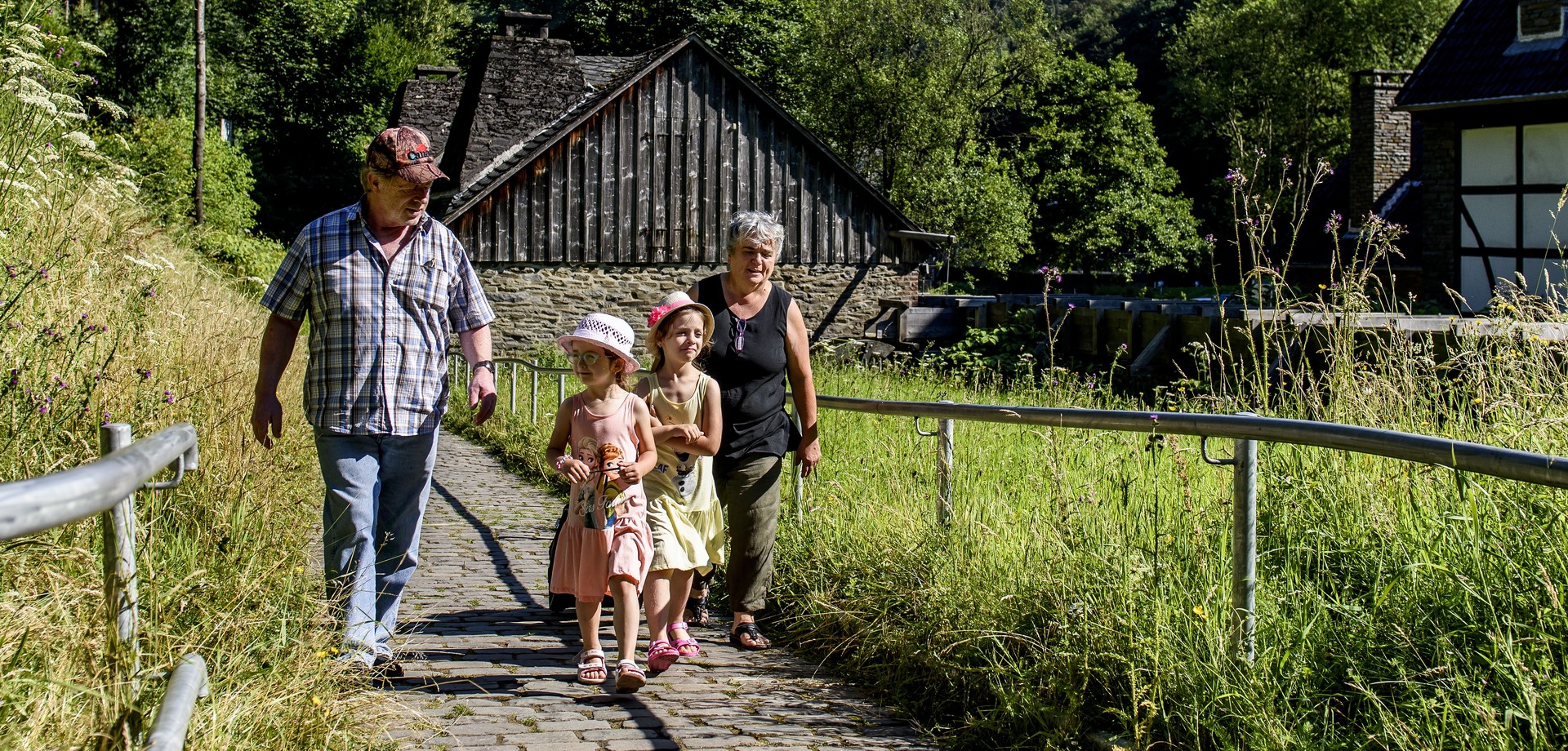 Großeltern mit zwei Enkelinnen gehen über das sommerliche Museumsgelände