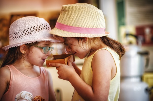 Zwei Mädchen mit Hut riechen an gemahlenem Kaffee