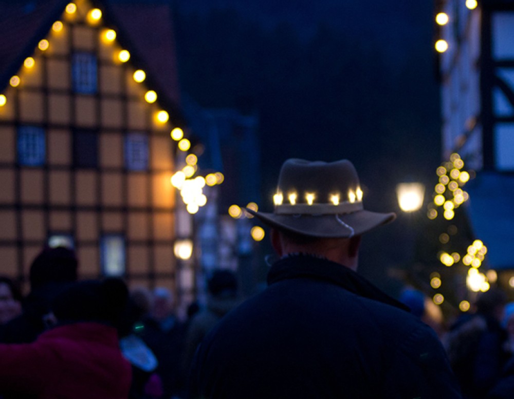 Ein Mann mit einem beleuchteten Hut auf einem Weihnachtsmarkt