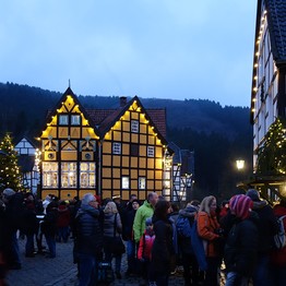 Besucher auf dem Weihnachtmarkt. Im Hintergrund ein gelbes Fachwerkhaus