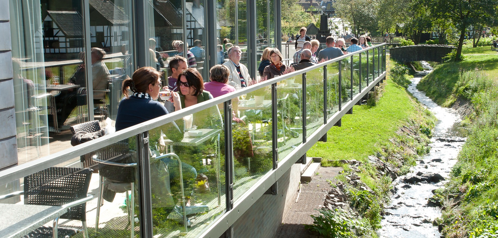 Menschen sitzen in der Sonne auf der Terrasse im Restaurant "Museumsterrassen"