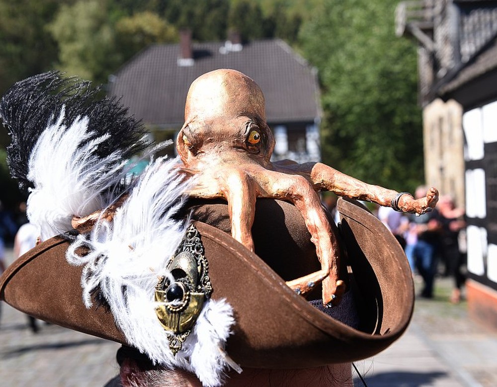 Das Bild zeigt einen Hut der mit einer Krake und Federn dekoriert ist