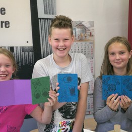 2 Mädchen und ein Junge präsentieren fröhlich ihre gebastelten Bücher