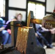 In Nahaufnahme schlägt ein Hammer auf ein glühendes Eisen auf einem Amboss